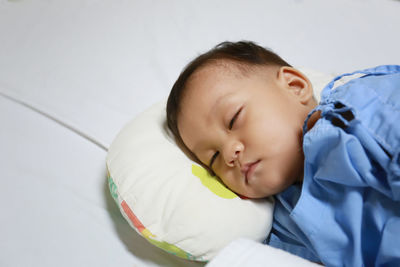 High angle view of cute boy sleeping on bed in hospital