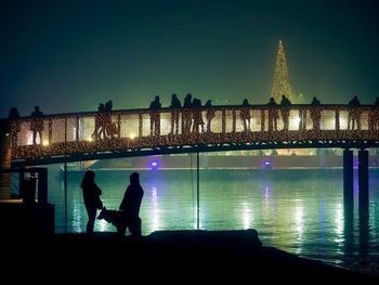 Man standing on bridge over river at night