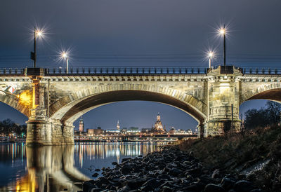Illuminated bridge over city against clear sky at night