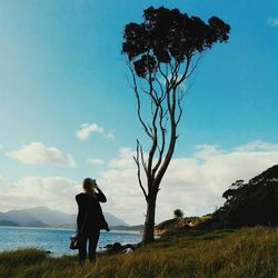 Full length of woman standing on landscape against blue sky