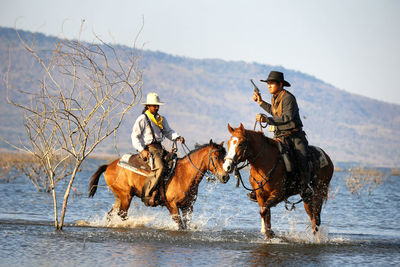 People riding horses in lake