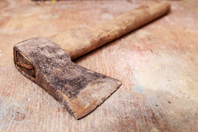 Close-up of rusty axe on wooden table