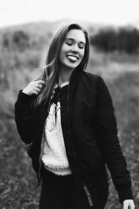 Portrait of smiling young woman standing on field