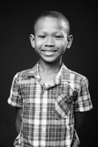 Portrait of smiling boy against black background