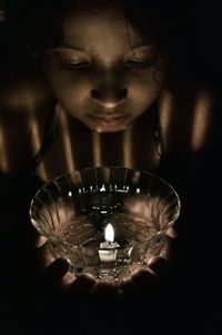 Close-up of woman with light candles in darkroom