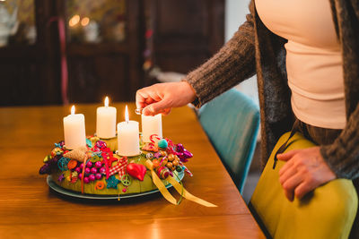 Midsection of woman lightning candles on cake at home