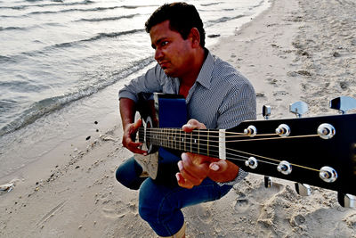 Man playing guitar at beach