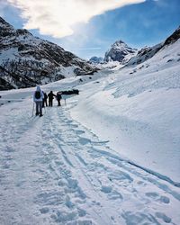 People walking on snowcapped mountain against sky