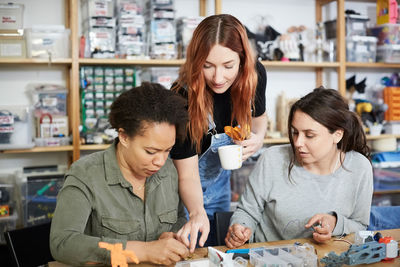 Redhead technician pointing to female coworkers at workshop