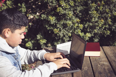 Young man writes on a laptop, in the park in the open air