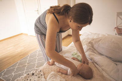 Rear view of woman sitting on bed at home