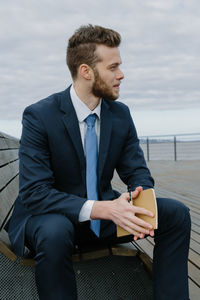 Young man sitting by sea