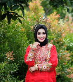 Portrait of smiling young woman standing against plants