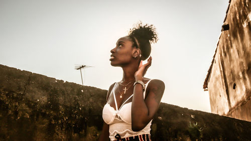 Young woman looking away against sky