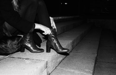 Low section of woman wearing boot on steps