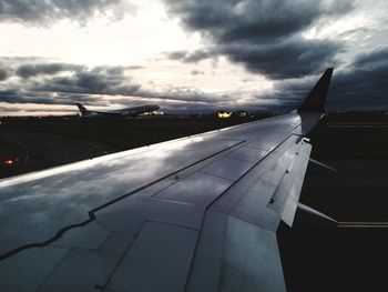 Airplane flying over airport runway against sky