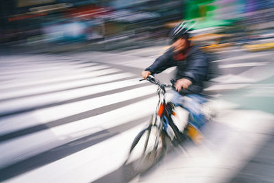 Blurred motion of man riding bicycle on road