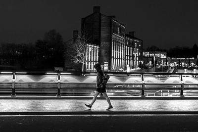 Blurred motion of man on illuminated street against buildings in city at night