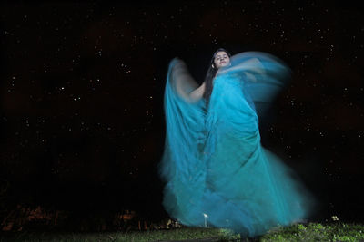Young woman dancing against star field at night