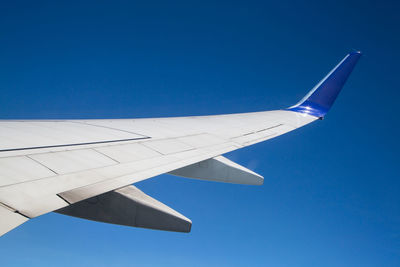 Close-up of airplane wing against clear blue sky