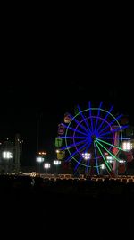 Illuminated ferris wheel against sky at night