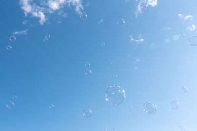 Low angle view of bubbles against blue sky