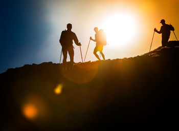 Silhouette men on mountain against sky during sunset