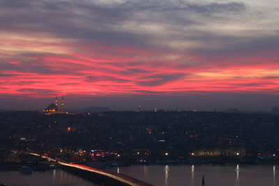 Illuminated buildings in city at sunset