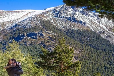 Woman photographing tree mountain during winter at navacerrada