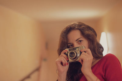 Portrait of woman photographing indoors