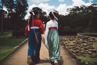 Rear view of women standing on footpath