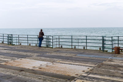 Peron leaning on railing of pier on sea