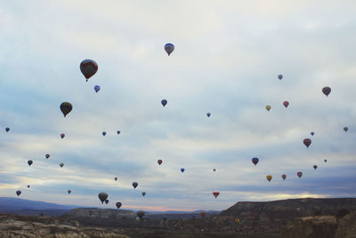 Hot air balloons over landscape against cloudy sky