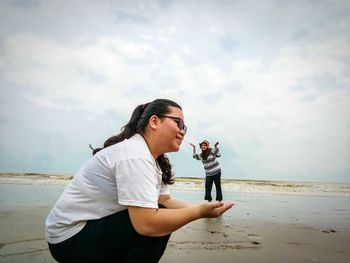 Young woman standing on beach against sky