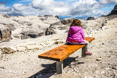 Rear view of woman sitting on top of the mountain 