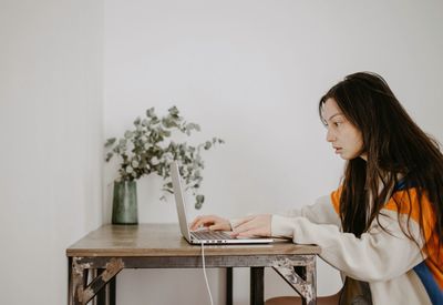 Portrait of young woman using laptop at home