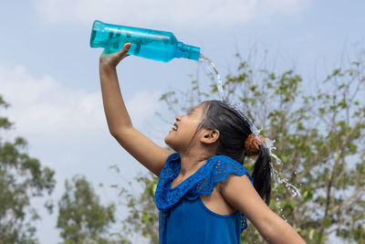 Side view of young woman drinking water bottle