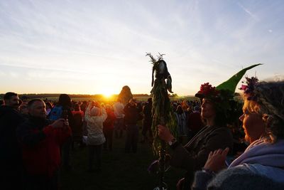 Crowd at music concert against sky during sunset