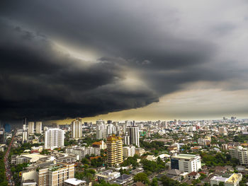 High angle view of buildings in city against storm clouds