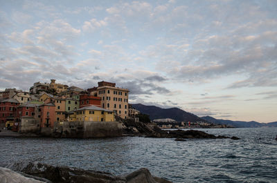 View of buildings at waterfront against cloudy sky