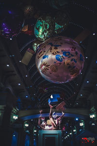 Low angle view of illuminated lighting equipment hanging at night