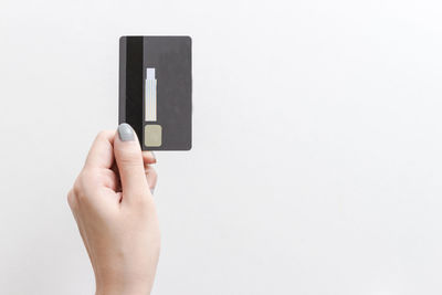 Close-up of hand holding camera against white background