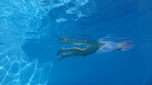 Low section of woman swimming in blue sea