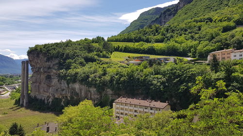 Built structure by trees and plants against sky