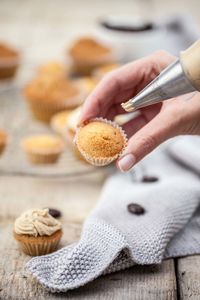 Cropped image of hand preparing cupcakes