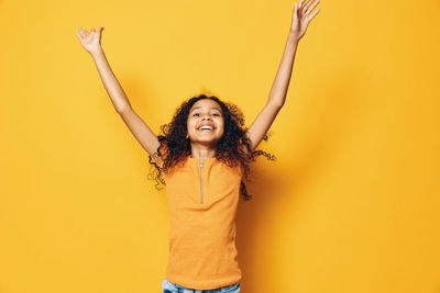 Portrait of young woman standing against yellow background