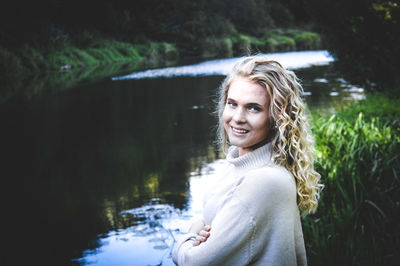 Portrait of woman with curly hair standing by lake