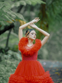 Portrait of young woman standing against trees