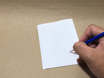 Low section of person holding paper against white wall