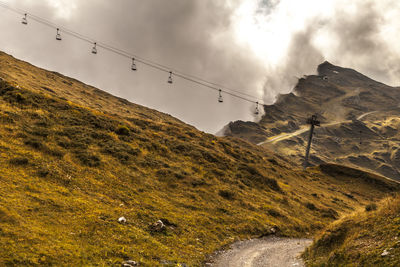 Side view of  chairlift againstcloudy  sky